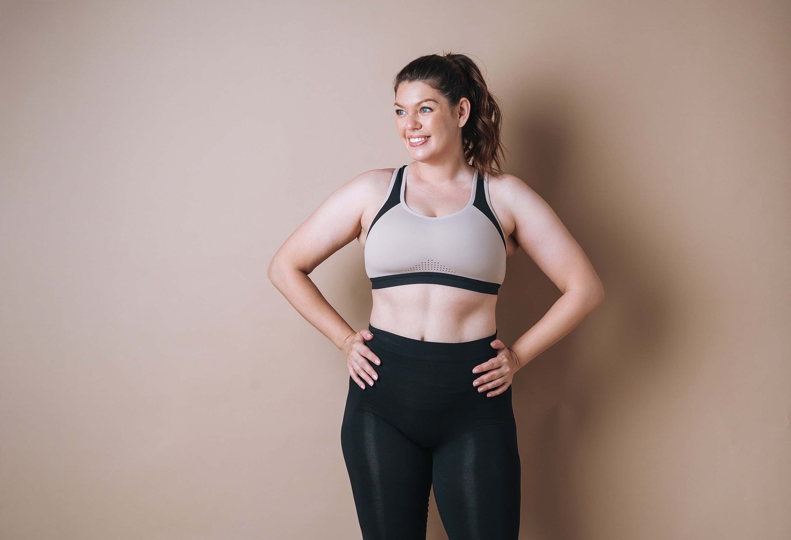 Smiling woman in activewear against plain background.